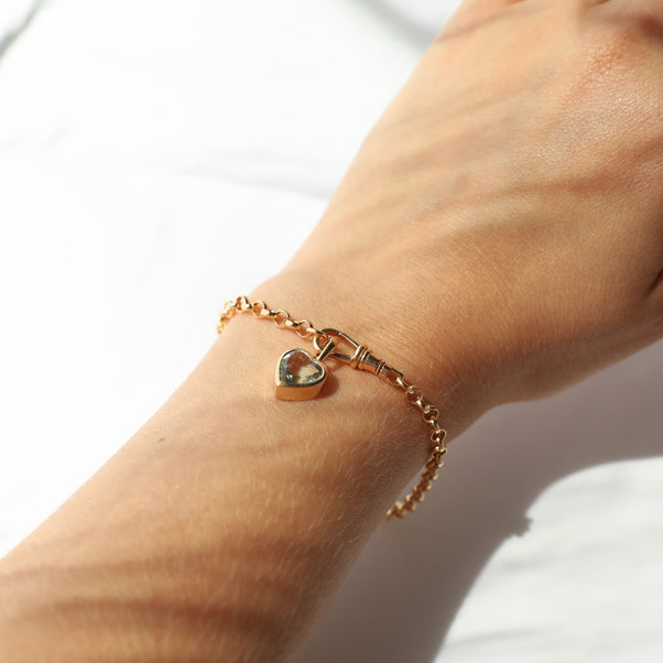 Carrie Elizabeth Gold bracelet with dogclip, a heart charm on a wrist against a white background